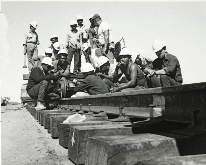 "A group of workers stop of a break on top of a railway line."